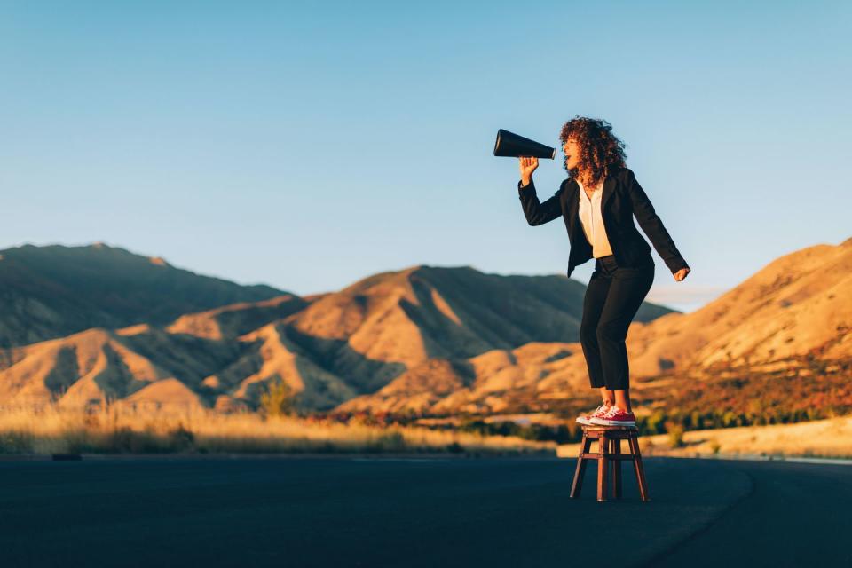 a businesswoman stands alone on a stool in a rural area of utah shouting through a megaphone waiting to be heard she is selling an idea that she believes will benefit her business and clients