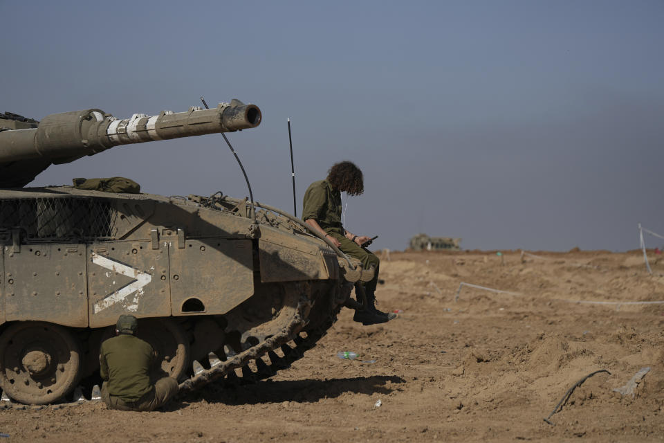 Israeli soldiers work on a tank in a staging area in southern Israel, near the border with Gaza Strip, on Friday, Nov. 24, 2023. the first day of what is meant to be a four-day cease-fire in the Israel-Hamas war. (AP Photo/Tsafrir Abayov)