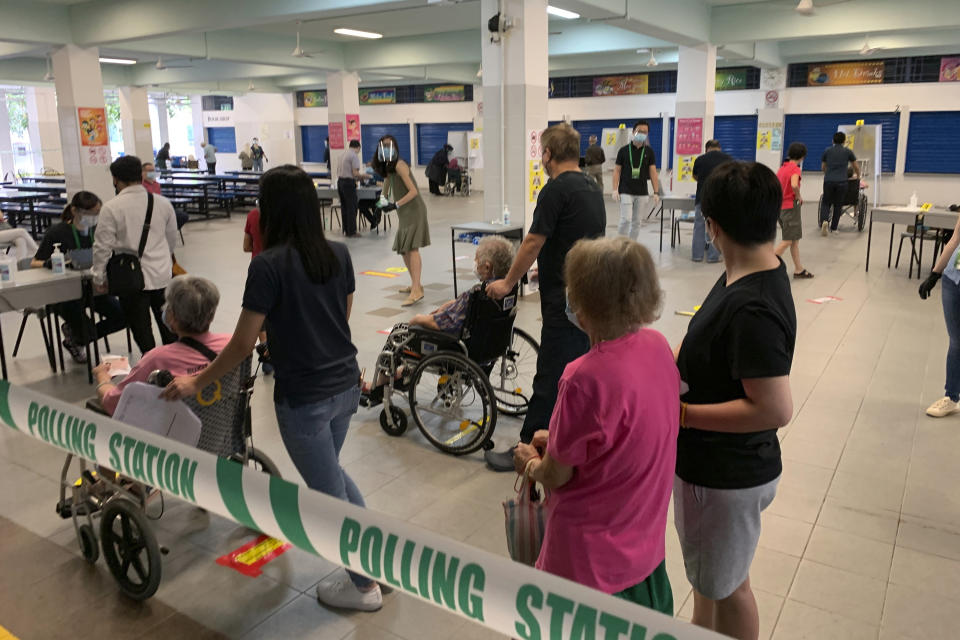 Voters wait for their turn inside the Dunearn Secondary School polling station in Singapore Friday, July 10, 2020. Wearing masks and plastic gloves, Singaporeans began voting in a general election that is expected to return Prime Minister Lee Hsien Loong's long-ruling party to power. (AP Photo/Royston Chan)