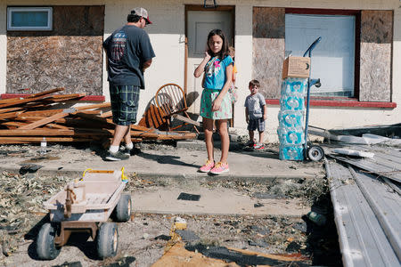 Hailey Strickland, 10, stands with her father Philip Strickland and her brothers as they carry water into their home in the aftermath of Hurricane Michael in Parker, Florida, U.S., October 13, 2018. REUTERS/Terray Sylvester