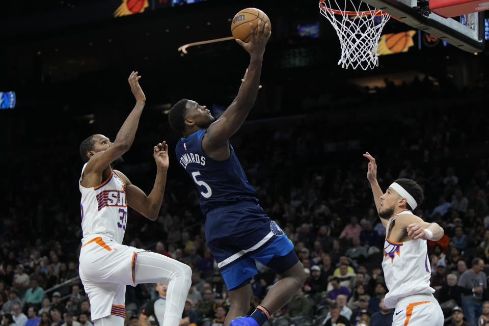 Minnesota Timberwolves guard Anthony Edwards drives between Phoenix Suns forward Kevin Durant (35) and guard Devin Booker during the second half of an NBA basketball game Friday, April 5, 2024, in Phoenix. (AP Photo/Rick Scuteri)