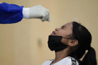 A medical worker collects a swab sample from a girl during coronavirus testing in Petaling Jaya, Malaysia, Monday, Jan. 18, 2021. Malaysian authorities imposed tighter restrictions on movement to try to halt the spread of the coronavirus. (AP Photo/Vincent Thian)