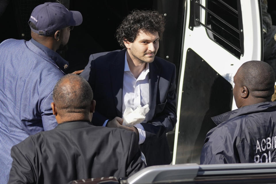 Sam Bankman-Fried, center, is escorted arrives at the Magistrate Court building for a hearing (Rebecca Blackwell / AP)