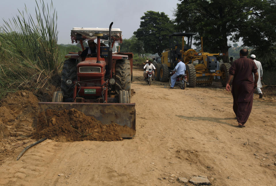 A worker uses a tractor to repair a portion of road damaged by a powerful earthquake, in Jatlan near Mirpur, in northeast Pakistan, Wednesday, Sept. 25, 2019. Thousands of people whose homes were damaged because of a strong earthquake are desperately waiting for the arrival of government help, 22 hours after the 5.8 magnitude tremor struck Pakistan-held Kashmir and elsewhere, killing 25 people and injuring 700. (AP Photo/Anjum Naveed)