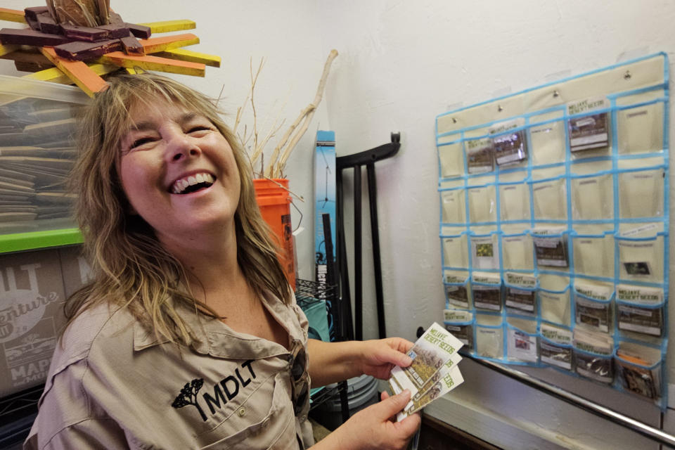 Jessica Dacey, director of communications at the Mojave Desert Land Trust, holds packages with hand-collected desert seeds at the Mojave Desert Seed Bank, Wednesday, June 12, 2023, near Joshua Tree, Calif. While seed banks started as a way to preserve rare and exotic plants in the U.S., they now also contain more commonly found seeds, which are increasingly in demand as climate change elevates the risk of natural disasters. (AP Photo/Damian Dovarganes)