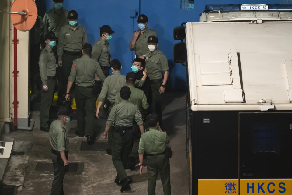 Joshua Wong, center right, one of the 47 pro-democracy Hong Kong activists, is escorted by Correctional Services officers to prison in Hong Kong, early Tuesday, March 2, 2021. Hong Kong police on Monday brought 47 pro-democracy activists to court on charges of conspiracy to commit subversion under the national security law imposed on the city by Beijing last year. (AP Photo/Kin Cheung)