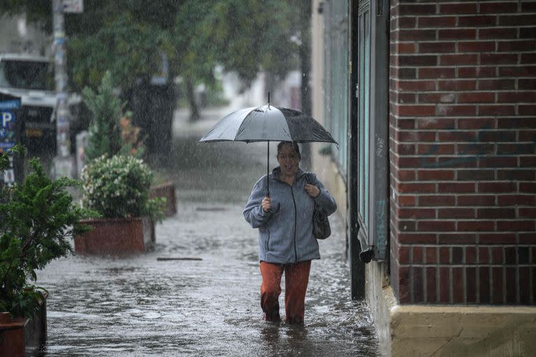 Una mujer con un paraguas camina a través del agua en Brooklyn, Nueva York, el 29 de septiembre de 2023. 