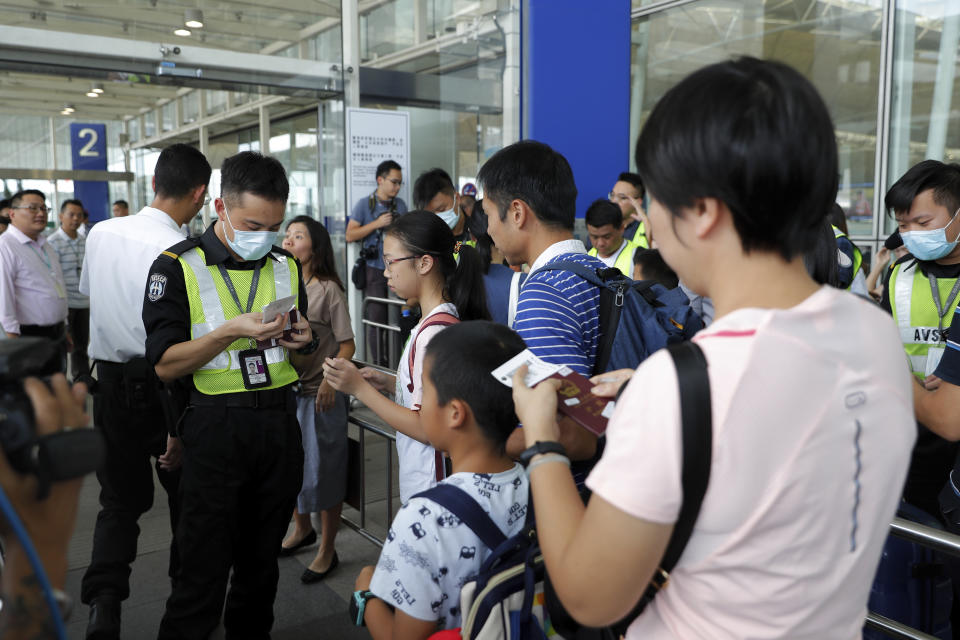 Airport security officers check on travelers' flights information at the airport main entrance gate in Hong Kong, Wednesday, Aug. 14, 2019. Flights resumed at Hong Kong's airport Wednesday morning after two days of disruptions marked by outbursts of violence that highlight the hardening positions of pro-democracy protesters and the authorities in the semi-autonomous Chinese city. (AP Photo/Vincent Thian)