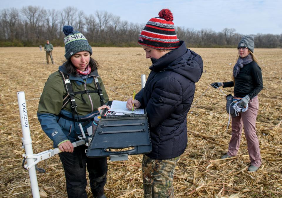 Volunteer Maggie Born, a Metamora Township High School senior, middle, writes down information from archaeologist Maria Meizis, left, about a grid in a cornfield being mapped for future excavation Thursday, Nov. 17, 2022 near Spring Bay. At far right is one of the directors of the project Dana Bardolph, an archaeologist from Northern Illinois University.