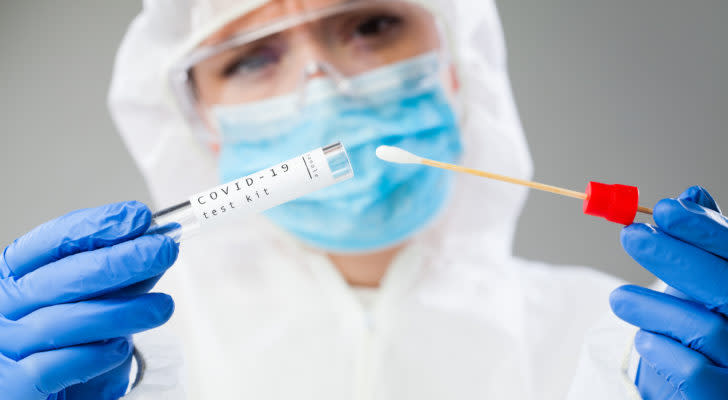 A Medical healthcare technologist holding COVID-19 swab collection kit, wearing white PPE protective suit mask gloves, test tube for taking OP NP patient specimen sample,PCR DNA testing protocol process