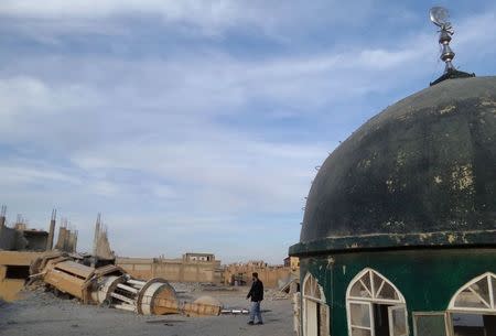 A man walks past a damaged mosque after what activists said were airstrikes by forces loyal to Syria's President Bashar al-Assad in Raqqa, eastern Syria, which is controlled by the Islamic State November 25, 2014. REUTERS/Nour Fourat