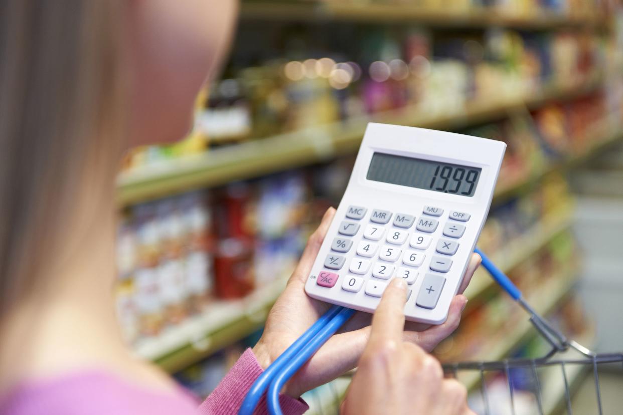 woman using calculator to cost shopping in supermarket