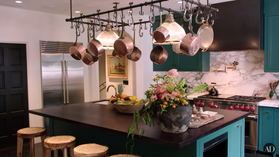 Another view of Kendall's kitchen with pots and pans hanging above an island table with stools
