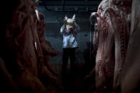 <p>An employee of the Mizra pork factory poses with a pig’s head in a refrigerated warehouse in Kibbutz Mizra, northern Israel, on Dec. 6, 2012. The million-strong Soviet immigrant community has increased customer demand for pork in the country, a non-kosher food rarely eaten by Israeli Jews. (Photo: Oded Balilty/AP) </p>