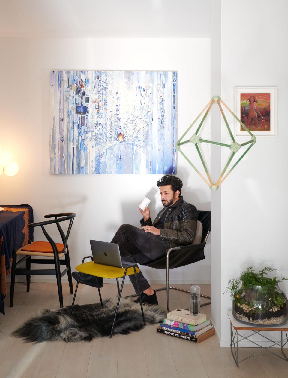 In his office nook on a Paulistano chair: paintings by Sarah Sze (above head) and Lisa Yuskavage; hanging sculpture by Olafur Eliasson.