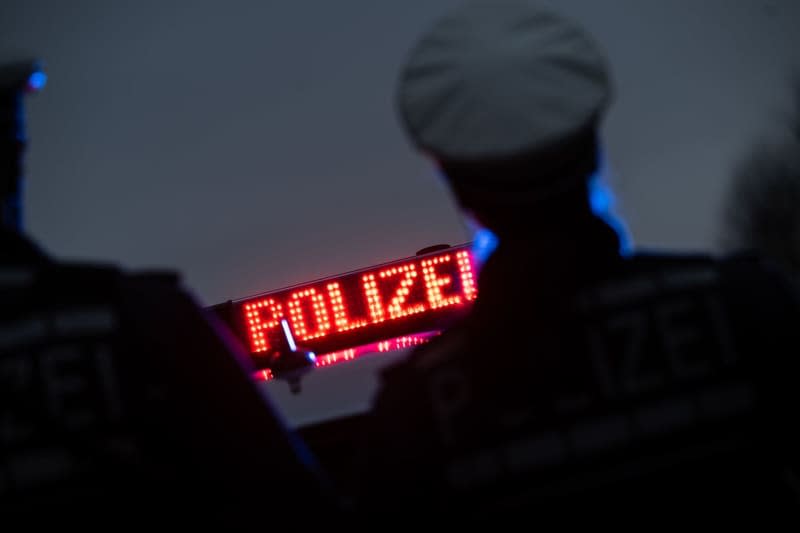 Two police officers stand in front of a police vehicle. Police in south-western Germany seized a large arsenal of weapons, including an assault rifle and a machine pistol, during a raid on a suspected drug dealer's home, authorities announced on Friday. Marijan Murat/dpa