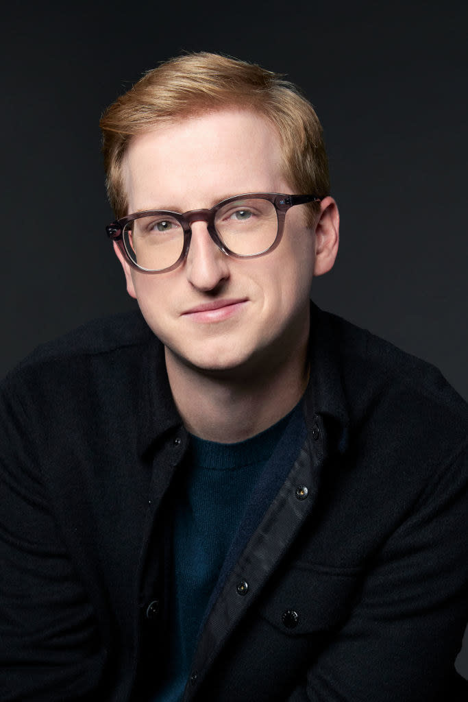 James in a professional photo wearing a dark-colored jacket and eyeglasses