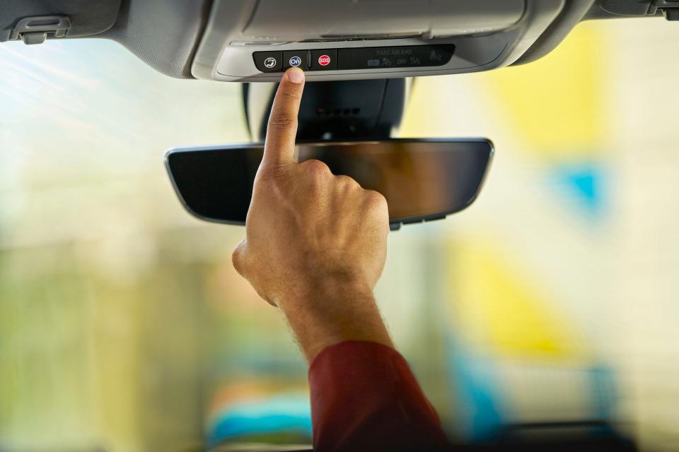 Person pushes the blue OnStar button in a GM vehicle.