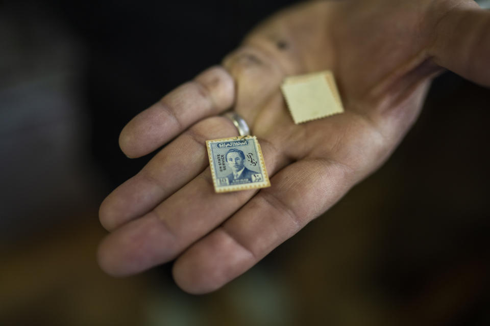 A man holds a vintage stamps featuring King Faisal II near Al-Mutanabbi street in Baghdad, Iraq, Friday, Feb. 24, 2023. (AP Photo/Jerome Delay)