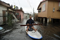 <p>A man uses a stand up paddle board to row down a street flooded by Hurricane Maria in Juana Matos, Catano, Puerto Rico, on Sept. 21, 2017. (Photo: Hector Retamal/AFP/Getty Images) </p>