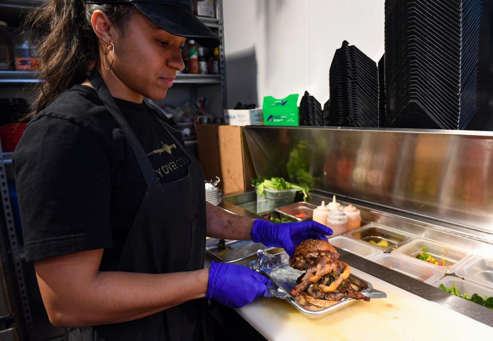 Del'Inkka Beaudion, owner of Swamp Daddy's Cajun Kitchen, places the final touches on the Banging 105 Burger as part of the downtown Burger Battle on Tuesday, January 4, 2022, in Sioux Falls.