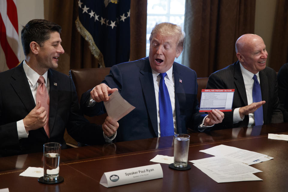 El presidente Donald Trump sostiene un ejemplo del posible aspecto que podría tener una nueva forma para pagar impuestos durante una reunión sobre políticas fiscales con legisladores republicanos en la Sala del Gabinete de la Casa Blanca, el jueves 2 de noviembre de 2017, en Washington. A la izquierda está el presidente de la Cámara de Representantes, el republicano Paul Ryan, y a la derecha el representante republicano Kevin Brady, presidente de la Comisión de Recursos y Arbitrios de la cámara baja. (AP Foto/Evan Vucci)