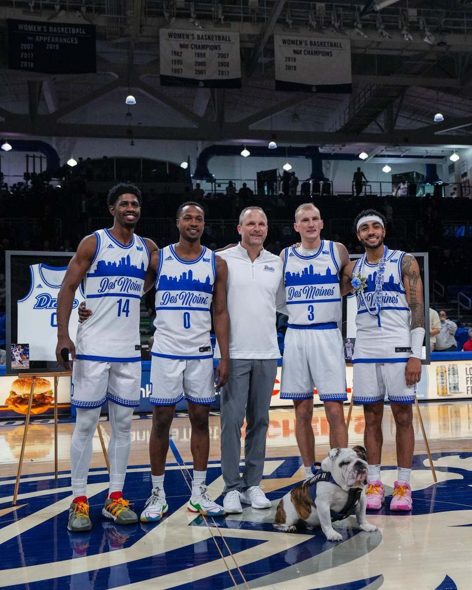 Drake seniors Sardaar Calhoun (14), left, D.J. Wilkins (0), head coach Darian DeVries, Garrett Sturtz (3), and Roman Penn (1) pose for a photo during senior night.