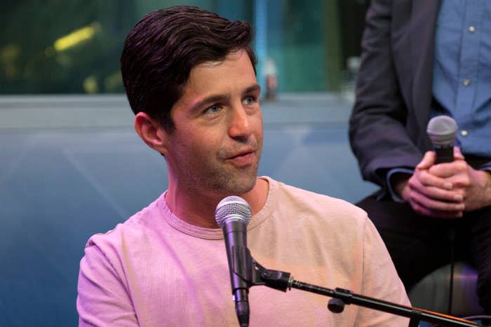 Josh in a t-shirt speaks into a microphone during an event