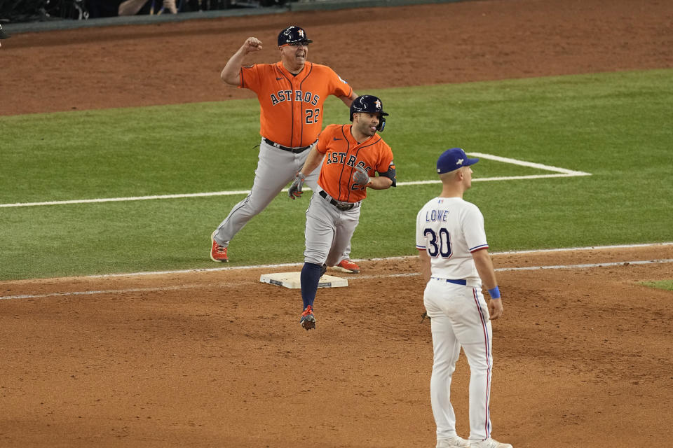 Houston Astros' Jose Altuve (27) runs the bases after hitting a three-run home run as first base coach Omar Lopez (22) celebrates and Texas Rangers first baseman Nathaniel Lowe (30) watches during the ninth inning in Game 5 of the baseball American League Championship Series Friday, Oct. 20, 2023, in Arlington, Texas. (AP Photo/Tony Gutierrez)