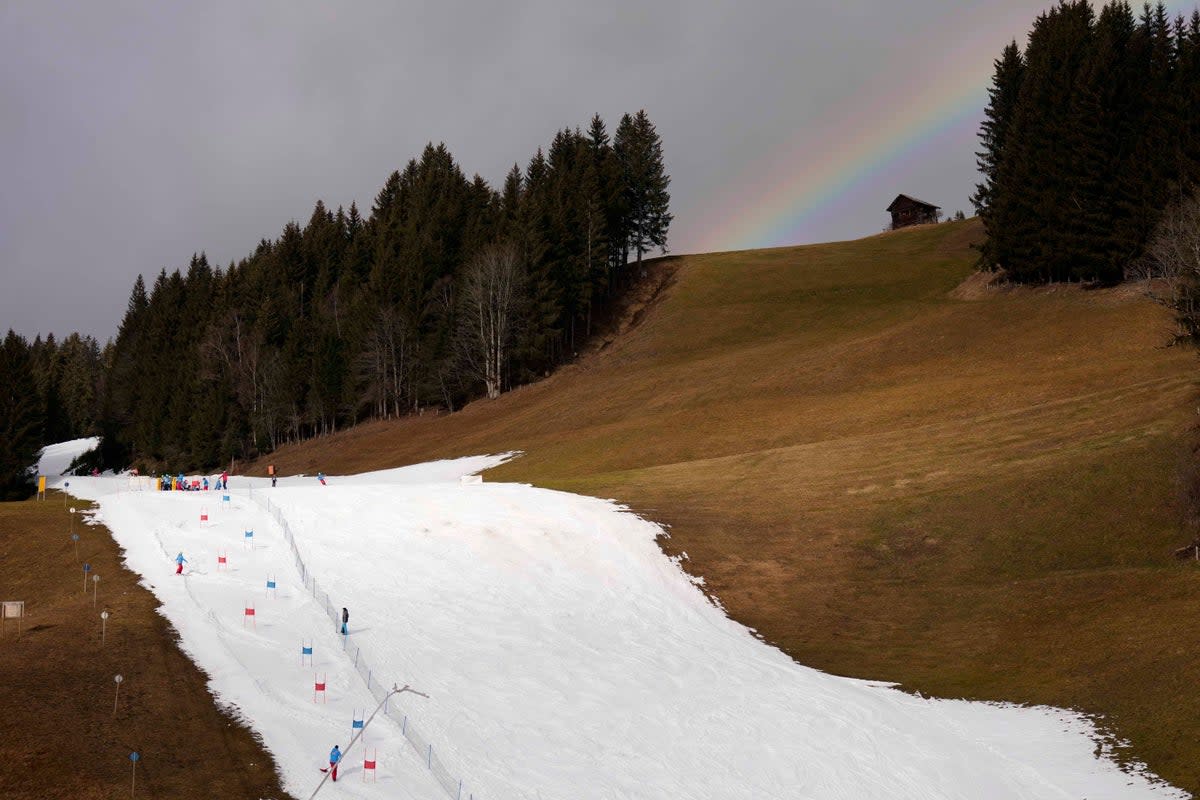 People skiing on a slope in Filzmoos south of Salzburg, Austria, Thursday, January 5, 2023. Sparse snowfall and unseasonably warm weather in much of Europe is allowing green grass to blanket many mountaintops  (AP)