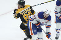 Boston Bruins right wing David Pastrnak (88) and Edmonton Oilers center Connor McDavid (97) work for position during the first period of an NHL hockey game Thursday, March 9, 2023, in Boston. McDavid, the NHL scoring leader, limped off the ice late in the third period. (AP Photo/Steven Senne)