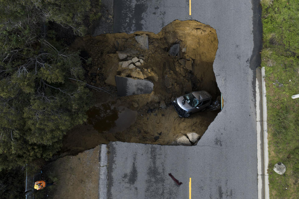 En esta imagen tomada con un dron se ve un vehículo dentro de un socavón, el martes 10 de enero de 2023, en Los Ángeles. (AP Foto/Jae C. Hong)