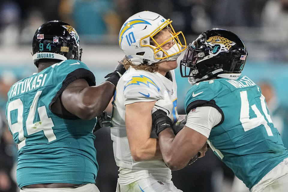 Los Angeles Chargers quarterback Justin Herbert (10) is hit by Jacksonville Jaguars linebacker Travon Walker (44) during the second of an NFL wild-card football game, Saturday, Jan. 14, 2023, in Jacksonville, Fla. (AP Photo/Chris Carlson)