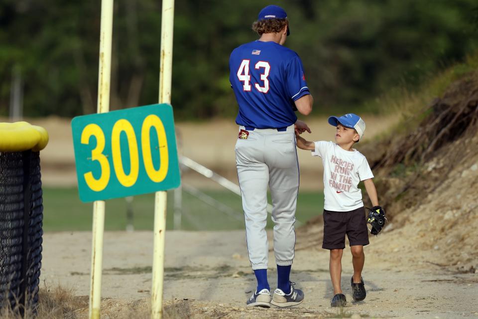 A young fan interacts with Chatham Anglers' Jack Seppings during a Cape Cod League baseball game against the Bourne Braves, Wednesday, July 12, 2023, in Bourne, Mass. For 100 years, the Cape Cod League has given top college players the opportunity to hone their skills and show off for scouts while facing other top talent from around the country. (AP Photo/Michael Dwyer)