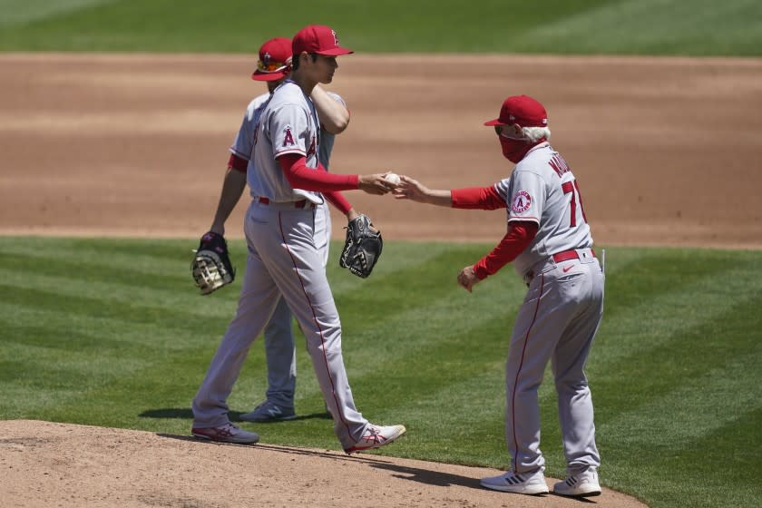 Angels manager Joe Maddon, right, takes the ball from Shohei Ohtani.