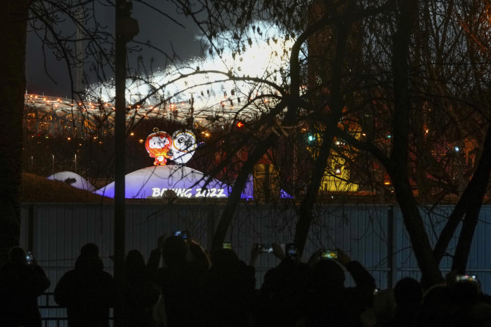 Residents film the fireworks explode over the iconic Bird's Nest Stadium during the opening ceremony of the 2022 Winter Olympics, in Beijing, Friday, Feb. 4, 2022. (AP Photo/Andy Wong)