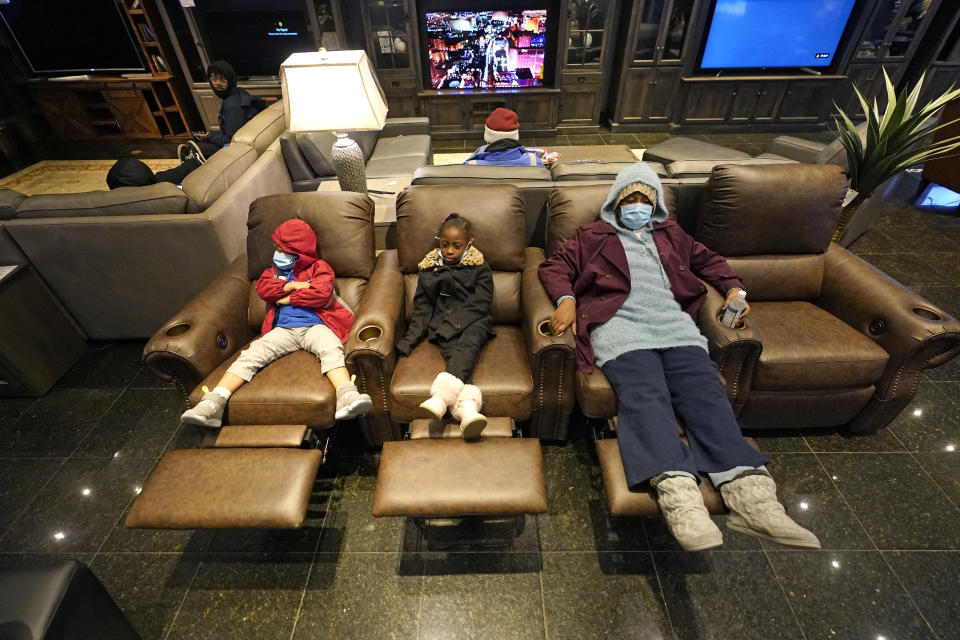 Joecyah Heath, left, Morning Day, center, and Jenesis Heath rest in recliners at a Gallery Furniture store which opened as a shelter Wednesday, Feb. 17, 2021, in Houston. Millions in Texas still had no power after a historic snowfall and single-digit temperatures created a surge of demand for electricity to warm up homes unaccustomed to such extreme lows, buckling the state's power grid and causing widespread blackouts. (AP Photo/David J. Phillip)