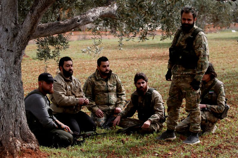 Rebel Ahmed Mansour and his group of fighters rest under an olive tree near Idlib