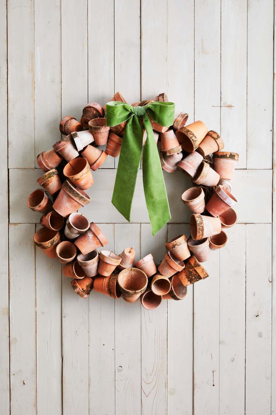 a large wreath made from terra cotta pots hung on a white barn door