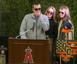 Family members of coach John Altobelli, his son J.J. Altobelli, left, with his fiancee Carly Konigsfeld, right, and his daughter Lexi Altobelli, speaks at a memorial service honoring their father John Altobelli, his wife Keri and their daughter Alyssa who were killed in a helicopter crash on Jan. 26, at Angel Stadium of Anaheim on Monday, Feb. 10, 2020, in Anaheim, Calif. (AP Photo/Damian Dovarganes)