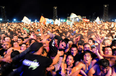 A man who was feeling unwell is passed over the barricade in the mosh pit area to security during a show of Argentine singer Indio Solari in Olavarria, Argentina, March 11, 2017. REUTERS/Stringer