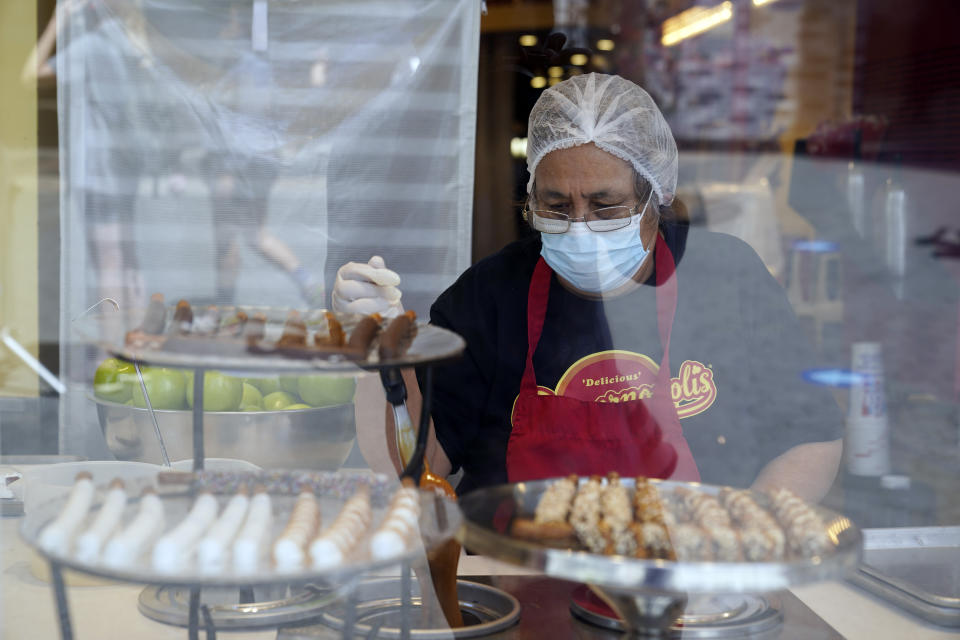 Una trabajadora usa una mascarilla mientras prepara postres en el Universal City Walk, el viernes 14 de mayo de 2021 en Universal City, California. (AP Foto/Marcio Jose Sanchez)