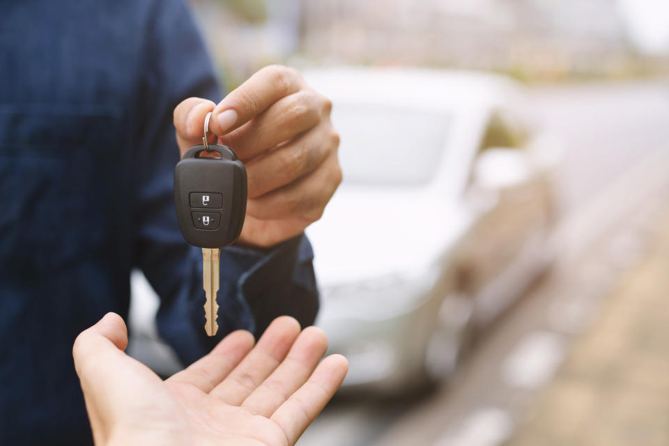 Person dropping a car key into another person's hand