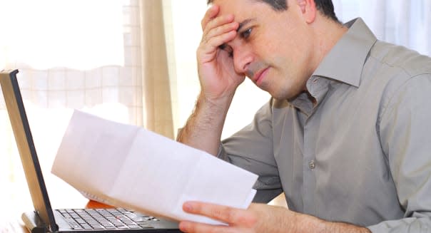 B2X945 Man sitting at his desk with a laptop and bills looking concerned. Image shot 2006. Exact date unknown.  man; businessman