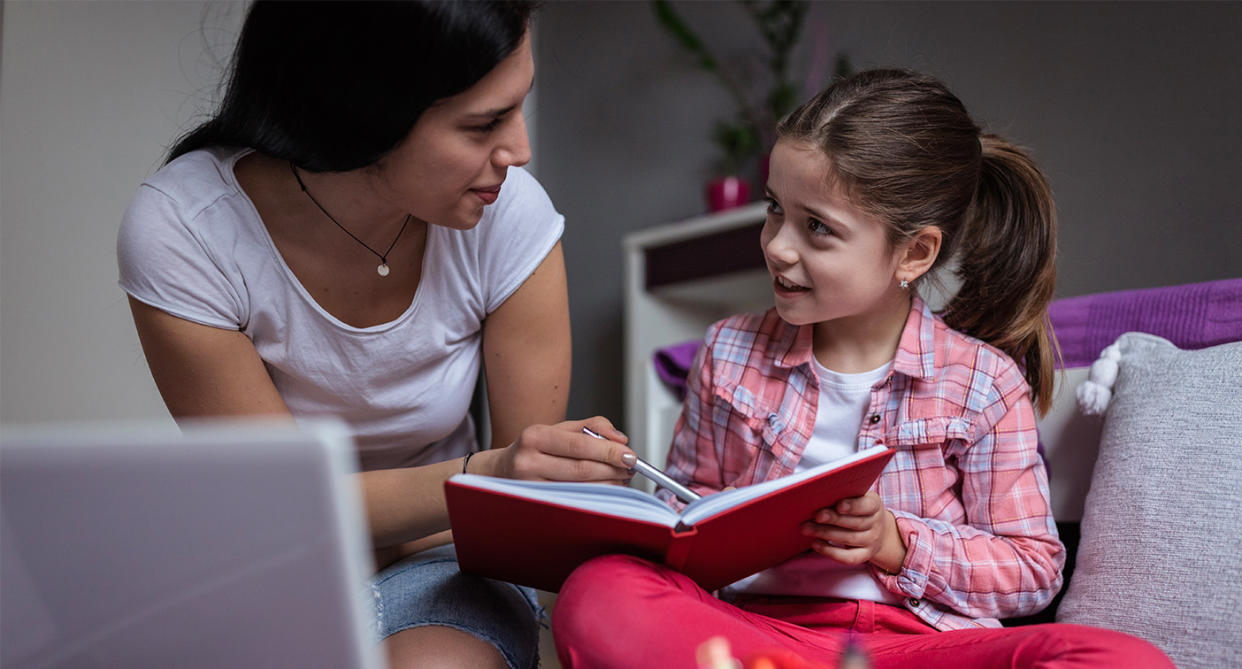 Eldest daughter syndrome, teenage girl helping younger sister with homework. (Getty Images)