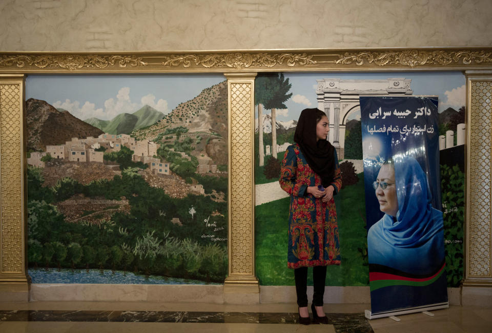 An Afghan female election worker and supporter of Habiba Sarabi, pictured on the placard, one of presidential candidate Zalmai Rassoul’s picks for vice president, waits for women to arrive for a meeting to discuss the upcoming elections in a hotel in Kabul, Afghanistan, Wednesday, March 26, 2014. A large number of women, including women parliamentarians attended the meeting saying they were there in solidarity with Sarabi, one of only three women chosen as running mates by presidential candidates, who can choose two vice presidents. The banner reads, "Habiba Sarabi - one woman who can stand up for any situation." (AP Photo/Anja Niedringhaus)