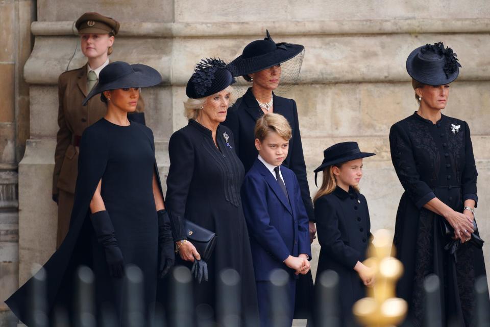 Meghan Markle, Queen Consort Camilla, Kate Middleton, the Countess of Wessex, Prince George, and Princess Charlotte stand outside of Westminster Abbey.