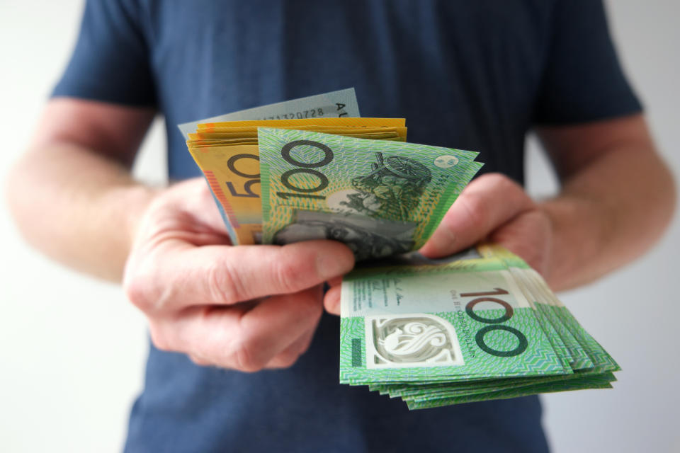 A man counting Australian dollar bills. A picture that describes buying, paying, handing out money, or showing money.