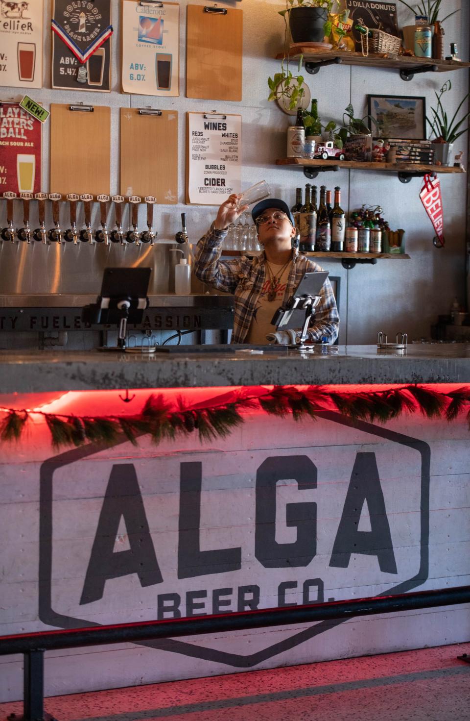 Bartender Angel Afalava polishes glasses at the Alga Beer Company in Pensacola on Wednesday, Jan. 4, 2023. The owners are planning on opening an '80s themed Florida Room cocktail bar in the building later this year.