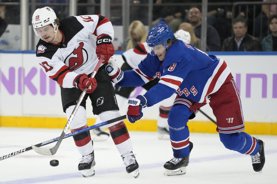 New Jersey Devils right wing Alexander Holtz (10) passes against New York Rangers defenseman Jacob Trouba (8) in the second period of an NHL hockey game, Monday, Nov. 28, 2022, in New York. (AP Photo/John Minchillo)